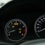 Lampă de control tracțiune auto, simbol galben aprins pe bord, indicând activarea sau defectarea sistemului de control al tracțiunii la vehicul.