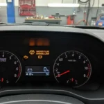 Lampă de avertizare lichid spălare parbriz aprinsă pe bordul unei mașini, indicând nivel scăzut al lichidului de spălare.